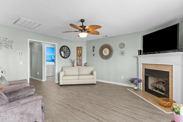 living room with visible vents, wood finished floors, washer / clothes dryer, a textured ceiling, and a ceiling fan