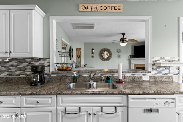 kitchen featuring a sink, visible vents, dark countertops, and dishwasher