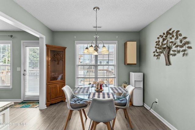 dining space featuring a wealth of natural light, baseboards, an inviting chandelier, and light wood-style flooring