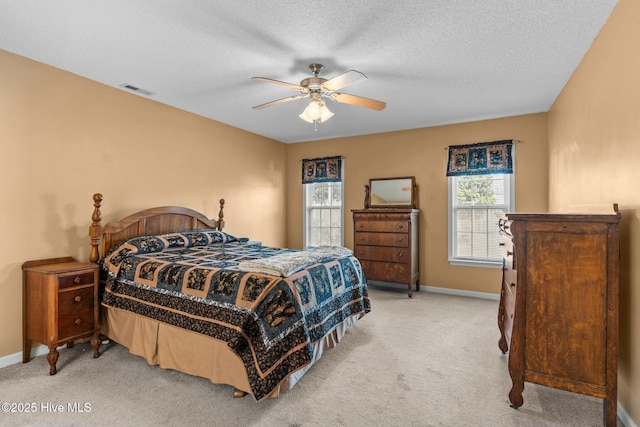 bedroom featuring a ceiling fan, baseboards, visible vents, a textured ceiling, and light carpet