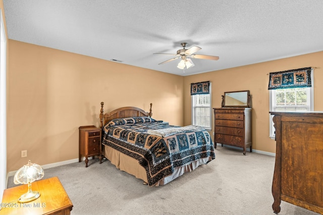 carpeted bedroom featuring visible vents, baseboards, a textured ceiling, and a ceiling fan