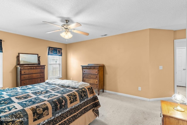 bedroom featuring visible vents, a ceiling fan, a textured ceiling, baseboards, and light colored carpet