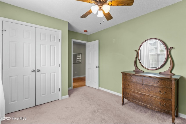 carpeted bedroom featuring a ceiling fan, baseboards, a closet, and a textured ceiling