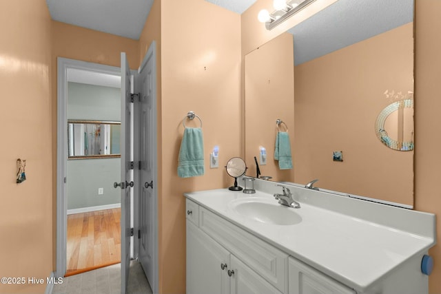 bathroom with baseboards, wood finished floors, and vanity