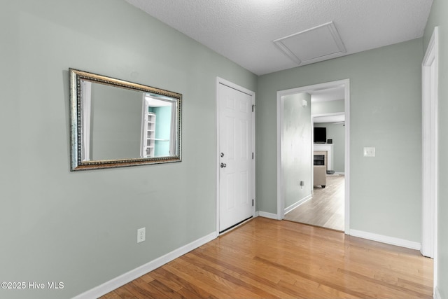 interior space featuring a fireplace, wood finished floors, baseboards, and a textured ceiling