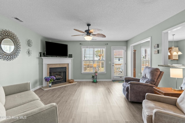 living room featuring visible vents, a tile fireplace, ceiling fan, and wood finished floors