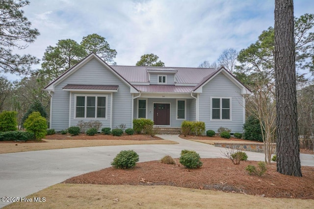 view of front facade featuring metal roof, covered porch, and curved driveway