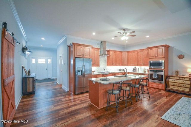 kitchen with dark wood-type flooring, wall chimney range hood, decorative backsplash, stainless steel appliances, and a sink