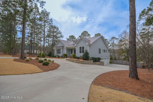 view of front of home featuring curved driveway, a garage, and fence