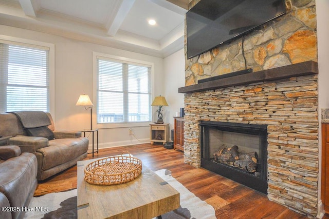 living area featuring beam ceiling, wood finished floors, a fireplace, crown molding, and baseboards