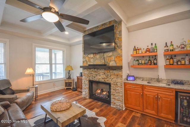 living room with indoor wet bar, a stone fireplace, wine cooler, and dark wood-type flooring