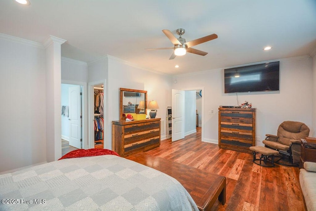 bedroom featuring a walk in closet, crown molding, recessed lighting, and wood finished floors