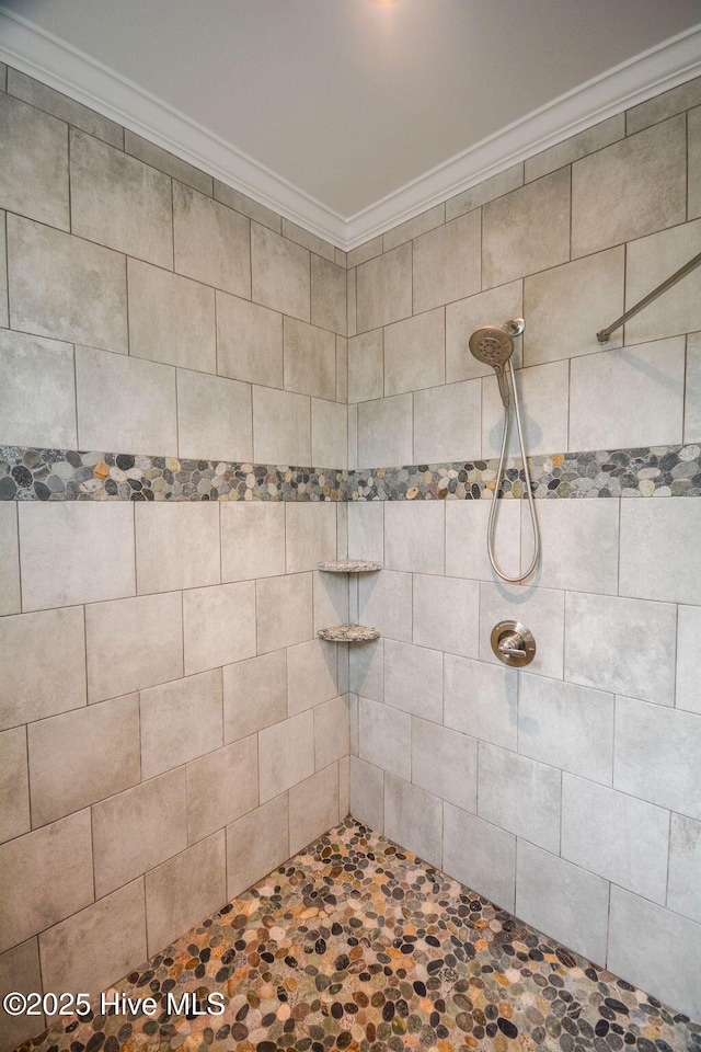 full bathroom with a tile shower and crown molding