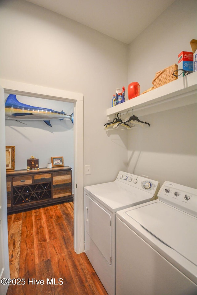 clothes washing area featuring wood finished floors, laundry area, and washer and clothes dryer