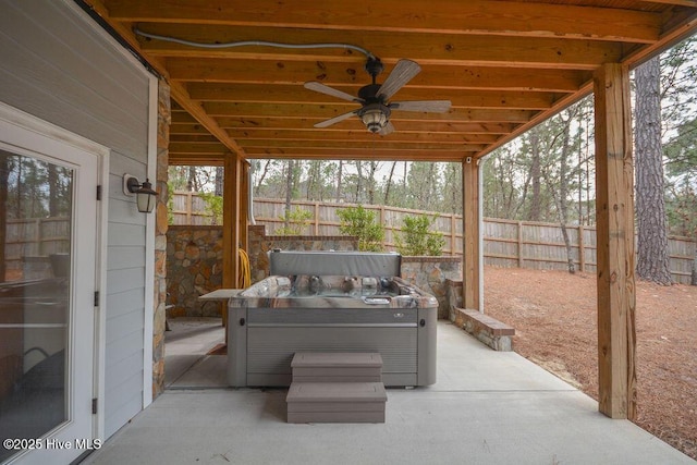 view of patio featuring a hot tub, a ceiling fan, and fence