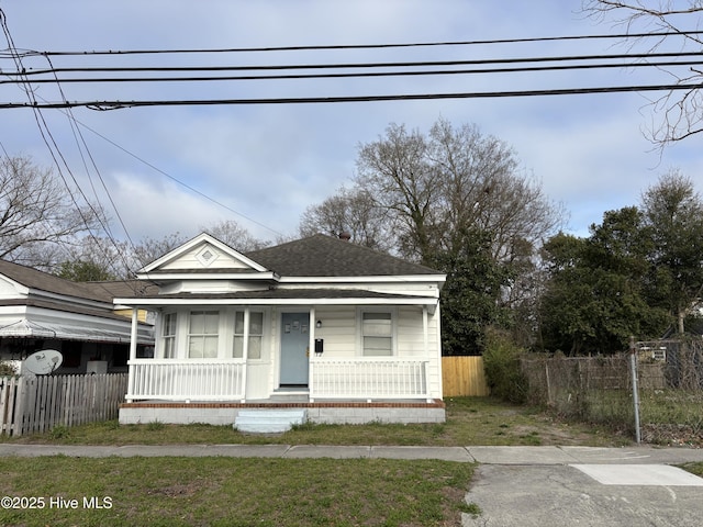 bungalow-style home with a porch, fence, and a shingled roof