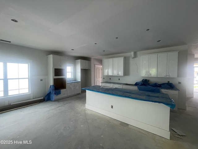 1514 Manta Ray Way, Sunset Beach, NC 28468 - kitchen featuring unfinished concrete floors, white cabinets, a kitchen island, and dark countertops