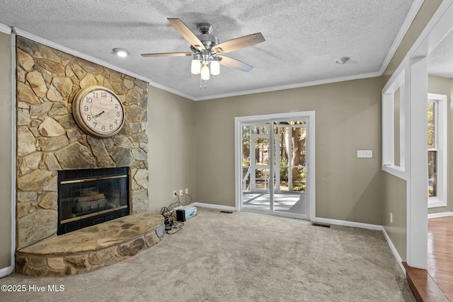 unfurnished living room with a stone fireplace, crown molding, carpet flooring, and ceiling fan