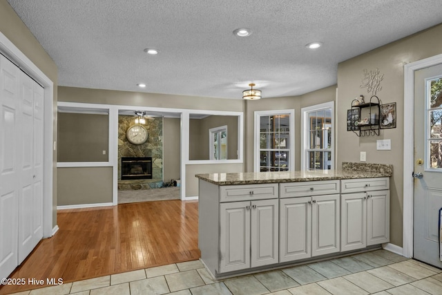 kitchen with light stone counters, a peninsula, a textured ceiling, and a fireplace