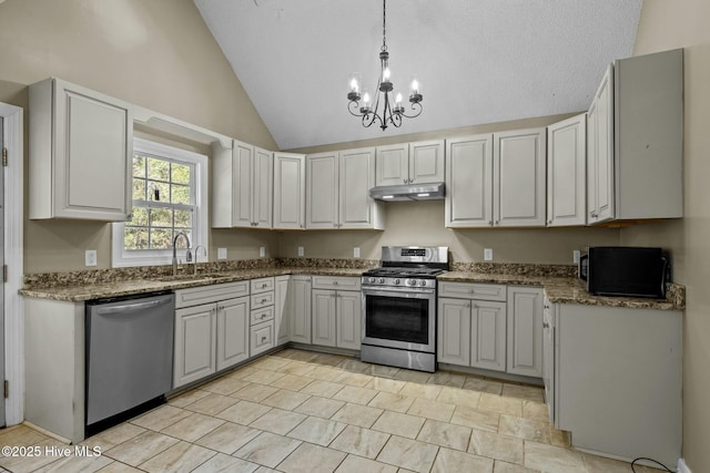 kitchen with a notable chandelier, under cabinet range hood, a sink, appliances with stainless steel finishes, and vaulted ceiling