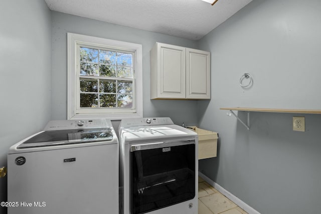 laundry area with baseboards, washer and dryer, cabinet space, a textured ceiling, and a sink