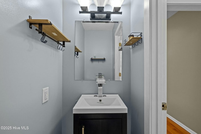 bathroom with vanity, wood finished floors, and baseboards