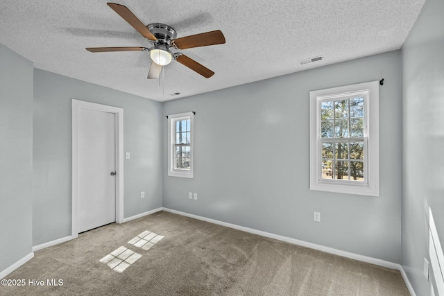 unfurnished room featuring visible vents, carpet floors, a healthy amount of sunlight, and a ceiling fan