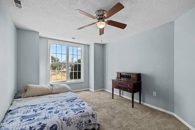 carpeted bedroom with ceiling fan, baseboards, visible vents, and a textured ceiling