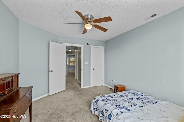 carpeted bedroom with visible vents, ceiling fan, a textured ceiling, and baseboards