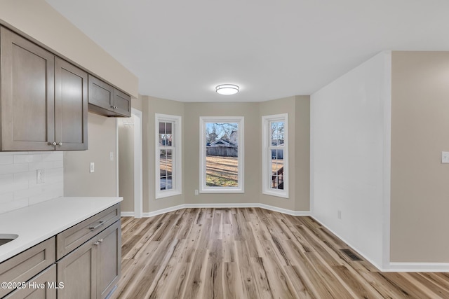 unfurnished dining area with light wood-style floors, visible vents, and baseboards