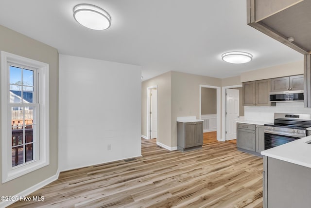 kitchen featuring light wood-type flooring, stainless steel appliances, light countertops, exhaust hood, and tasteful backsplash