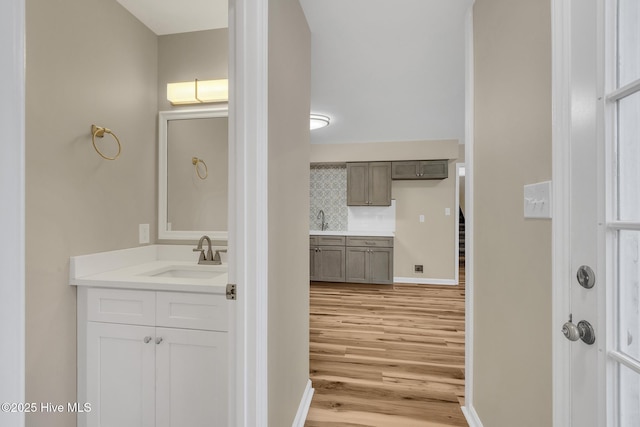 bathroom featuring baseboards, tasteful backsplash, wood finished floors, and vanity