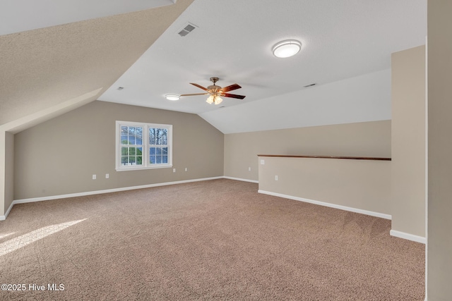 additional living space featuring visible vents, carpet, baseboards, vaulted ceiling, and a textured ceiling