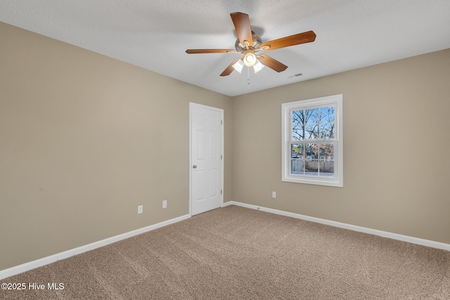 carpeted spare room featuring visible vents, baseboards, and ceiling fan