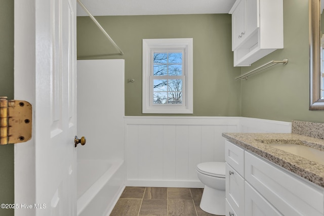 full bathroom featuring wainscoting, toilet, vanity, and shower / bathing tub combination