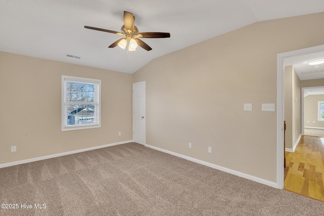 empty room with vaulted ceiling, light carpet, visible vents, and ceiling fan