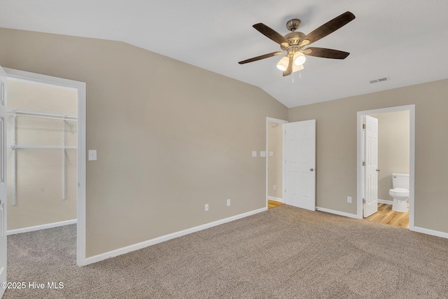 unfurnished bedroom featuring visible vents, carpet floors, baseboards, a spacious closet, and vaulted ceiling