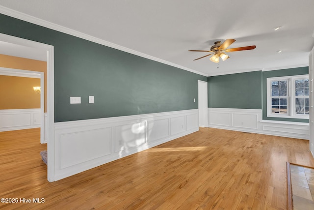 unfurnished room with a wainscoted wall, crown molding, ceiling fan, and wood finished floors