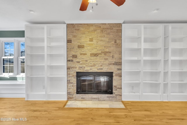 unfurnished living room with wood finished floors, crown molding, a fireplace, and ceiling fan