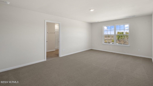 carpeted spare room with visible vents and baseboards