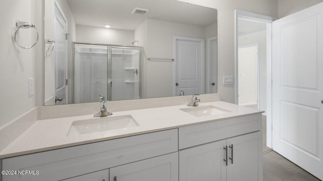 bathroom with a shower stall, double vanity, visible vents, and a sink