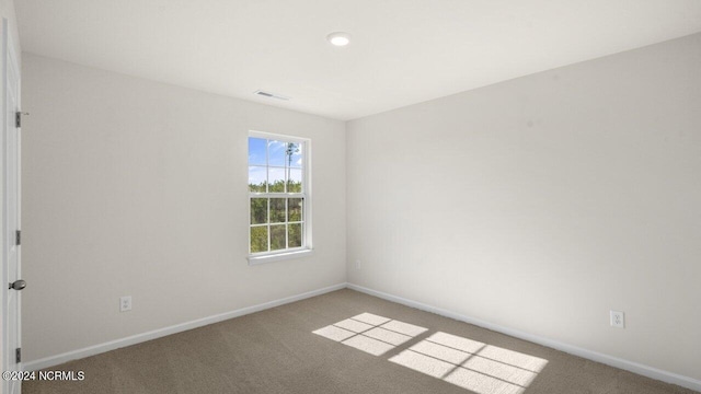 spare room with visible vents, baseboards, and carpet