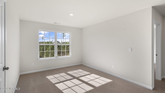 carpeted spare room featuring visible vents and baseboards