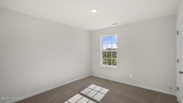 carpeted spare room featuring visible vents and baseboards