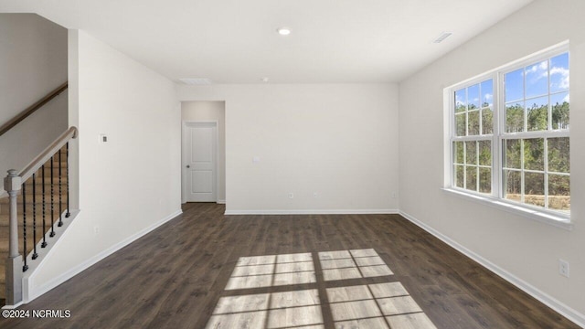 unfurnished room with visible vents, baseboards, dark wood-style floors, and stairs