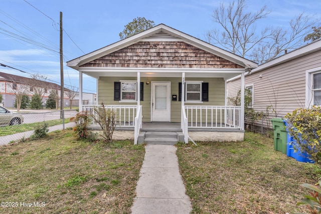 view of front of property featuring covered porch, a front yard, and fence