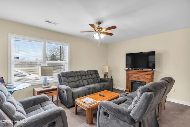 living room featuring a fireplace, a ceiling fan, visible vents, and baseboards