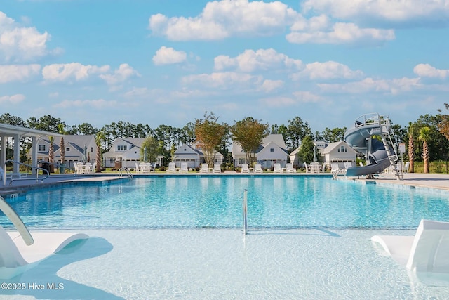 pool featuring a patio area, a residential view, and a water slide