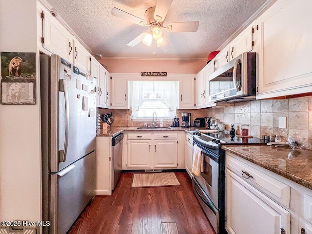 kitchen with dark wood-type flooring, a sink, appliances with stainless steel finishes, stone counters, and decorative backsplash