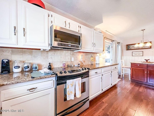 kitchen with appliances with stainless steel finishes, wood finished floors, a notable chandelier, a textured ceiling, and white cabinetry